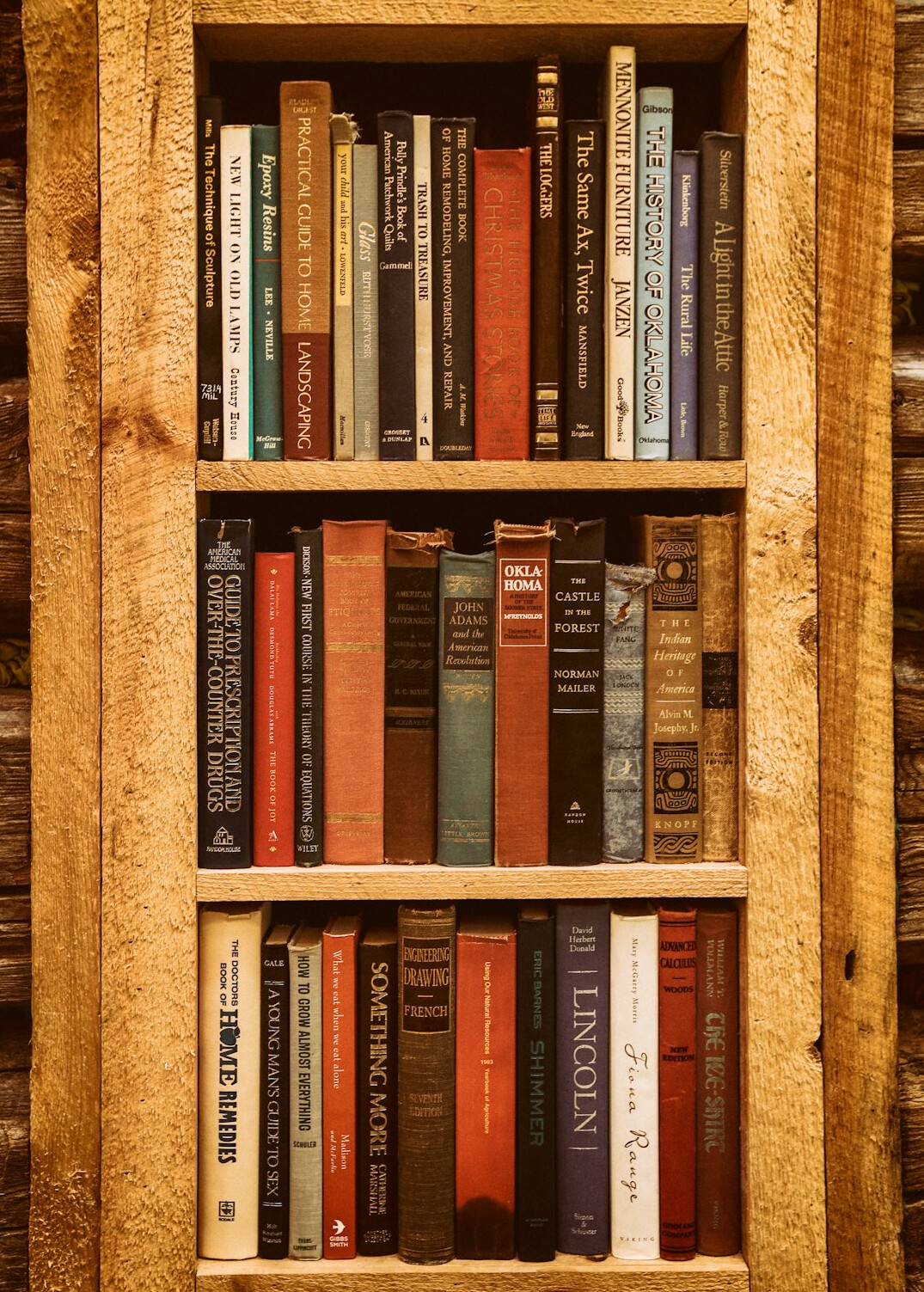 Tall wooden bookshelf filled with old hardcover novels